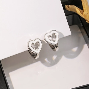 Vue macro des boucles d'oreilles cœur en argent avec émail blanc sur écrin à bijoux