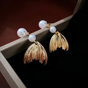 Elegant fishtail pearl earrings with gold brushed metal finish in a luxury jewelry box