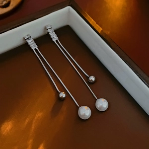 Detail of silver long chain tassel earrings with white pearls and sparkling zircons