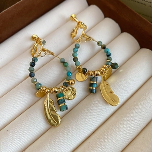Detailed shot of bohemian gold feather earrings with turquoise beads in a jewelry box