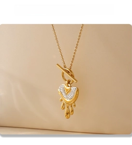 Detailed shot of a gold-plated melting heart pendant with OT buckle and shiny zircon stones