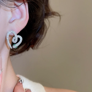 Close-up of heart-shaped snake earrings with silver plating and sparkling crystals