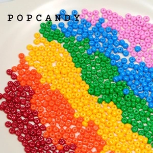 Detailed macro view of colorful 2mm glass seed beads arranged in a vibrant rainbow pattern
