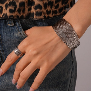 Detail of silver textured multi-layer cuff bracelet and matching ring set worn with outfit