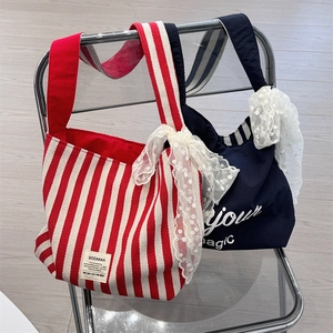 Detail of canvas tote bags with striped patterns and delicate white lace bow accents