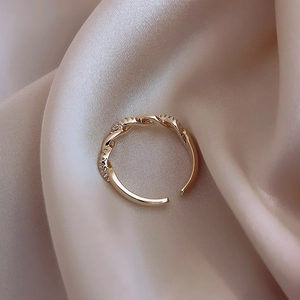 Detailed view of gold twisted braid ring with micro-inlaid zircon on silk background