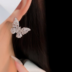 Macro shot of silver butterfly stud earrings with sparkling cubic zirconia on ear