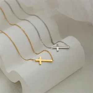 Minimalist stainless steel cross necklace available in gold and silver finishes on display