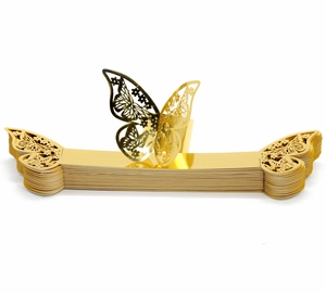 Detailed macro view of laser-cut gold butterfly napkin rings stacked on a white background