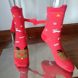 Detail of red Christmas socks featuring 3D magnetic hands and reindeer embroidery