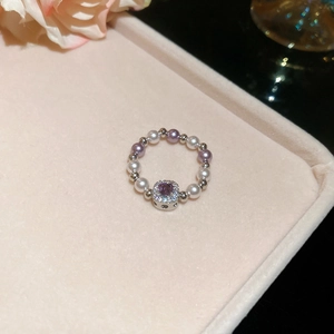 Macro shot of a beaded ring featuring a purple square stone and white pearls on velvet