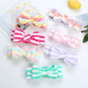 Detailed overhead view of assorted striped coral fleece bow headbands in soft pastel colors