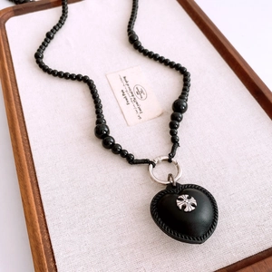 Detailed macro view of black beaded necklace with leather heart pendant and metal cross icon