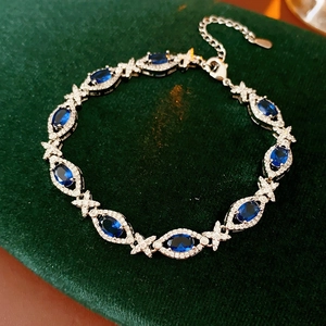 Macro shot of vintage silver bracelet with blue oval zircon on green velvet background
