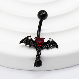 Détail d'un piercing nombril gothique avec ailes de chauve-souris et gemme cœur rouge