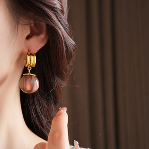 Close-up of a model wearing retro irregular resin drop earrings in smoky brown and gold