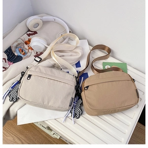 Détail de sacs à bandoulière en nylon macaron avec breloque damier sur valise blanche