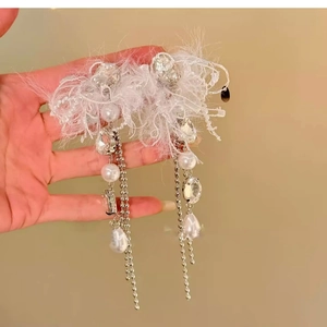 Détail de boucles d'oreilles avec plumes blanches, perles et chaînes à pampilles