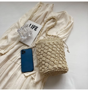 Top view of woven straw bucket bag with drawstring and shoulder strap on dress