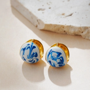Detail of 18K gold plated hoop earrings with blue and white marble enamel finish