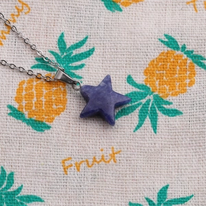 Detail shot of a dark blue star-shaped stone pendant with a silver metal necklace chain