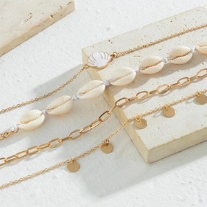 Detail of multi-layered gold anklet set with natural shells and pendants on a stone base