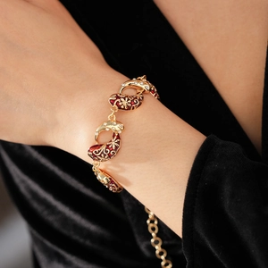Detail of vintage gold bracelet with red enamel and crystals on female model