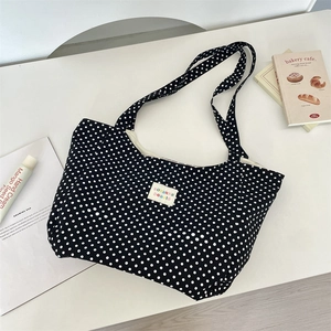 Detailed macro view of black polka dot canvas tote bag featuring sozakka logo on a desk