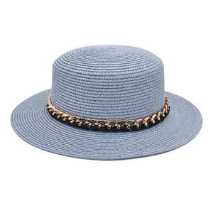 Détail d'un canotier en paille bleu clair avec chaîne dorée et ruban en cuir noir