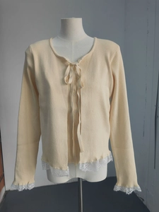 Détail du cardigan en maille crème avec bordure en dentelle et poignets évasés