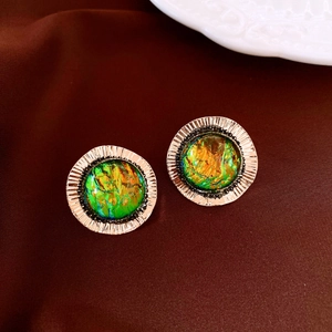 Detail of vintage round stud earrings featuring iridescent green resin and golden metal