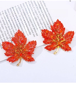Detail of maple leaf brooches with red rhinestone gradients in more and fewer gemstone versions