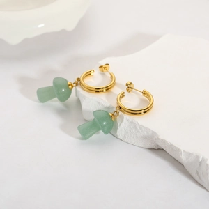 Close-up of 18K gold C-shaped earrings featuring natural green stone mushroom charms