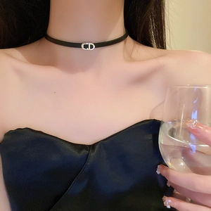 Close-up of black faux leather choker with silver CD logo on a woman's neckline