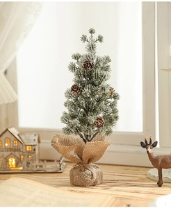 Mini tabletop snowy Christmas tree with pine cones and burlap base in a festive setting