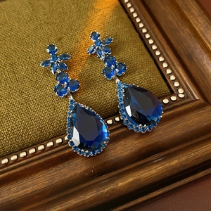 Detailed view of teardrop sapphire earrings with zircon flower studs on vintage background