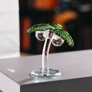Macro detail of crystal coconut tree figurine with green leaves on a grey book base