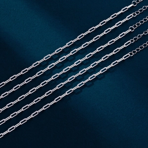 Macro shot of silver paperclip link chains with adjustable clasp on deep blue background