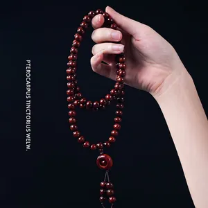 Polished 108 sandalwood beads necklace with tassel and pingan-kou charm held by hand