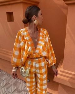 Detail of orange checkered deep V-neck crop top with puff sleeves and matching high waist pants