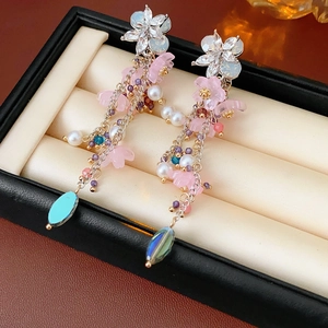 Dettaglio di orecchini vintage in argento con motivi floreali, perle bianche e nappe