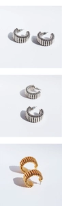 Detailed macro view of gold and silver C-shaped wave spiral hoop earrings for women