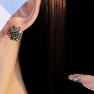 Detail of vintage flower stud earring with green gemstone on model showing retro style
