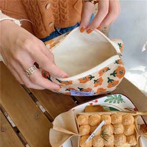 Détail de la trousse de maquillage en velours côtelé avec imprimé floral et zip blanc