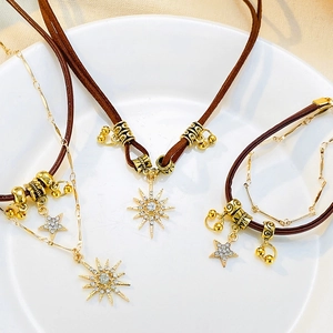 Detail of bohemian sun and star pendants on brown leather cord necklace and bracelet