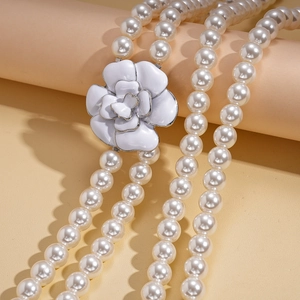 Detail of multi-layer pearl necklace featuring a white enamel camellia flower pendant