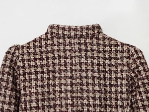 Detailed close-up of tweed blazer with red, black, and white woven fabric and stand collar