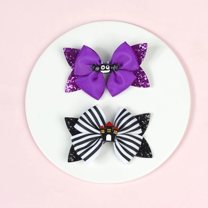 Macro detail of Halloween sequin bow hair clips with purple bat and ghost house charm