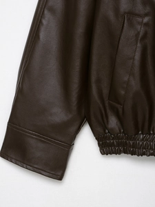 Detail of dark brown faux leather bomber jacket showing elastic hem and pocket texture