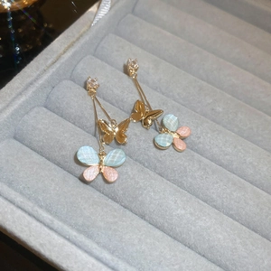 Detail of gold butterfly tassel earrings with blue pink mesh wings and zircon accents